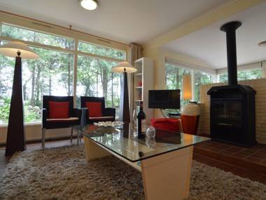 A detached bungalow with outdoor fireplace covered terrace and pond in a forest plot